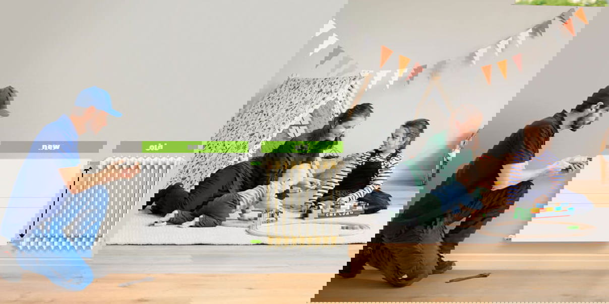 Installer fitting a new flat panel radiator next to an old column radiator in a family home.