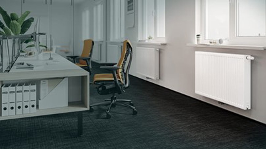 White panel radiator installed under window in a modern office space.